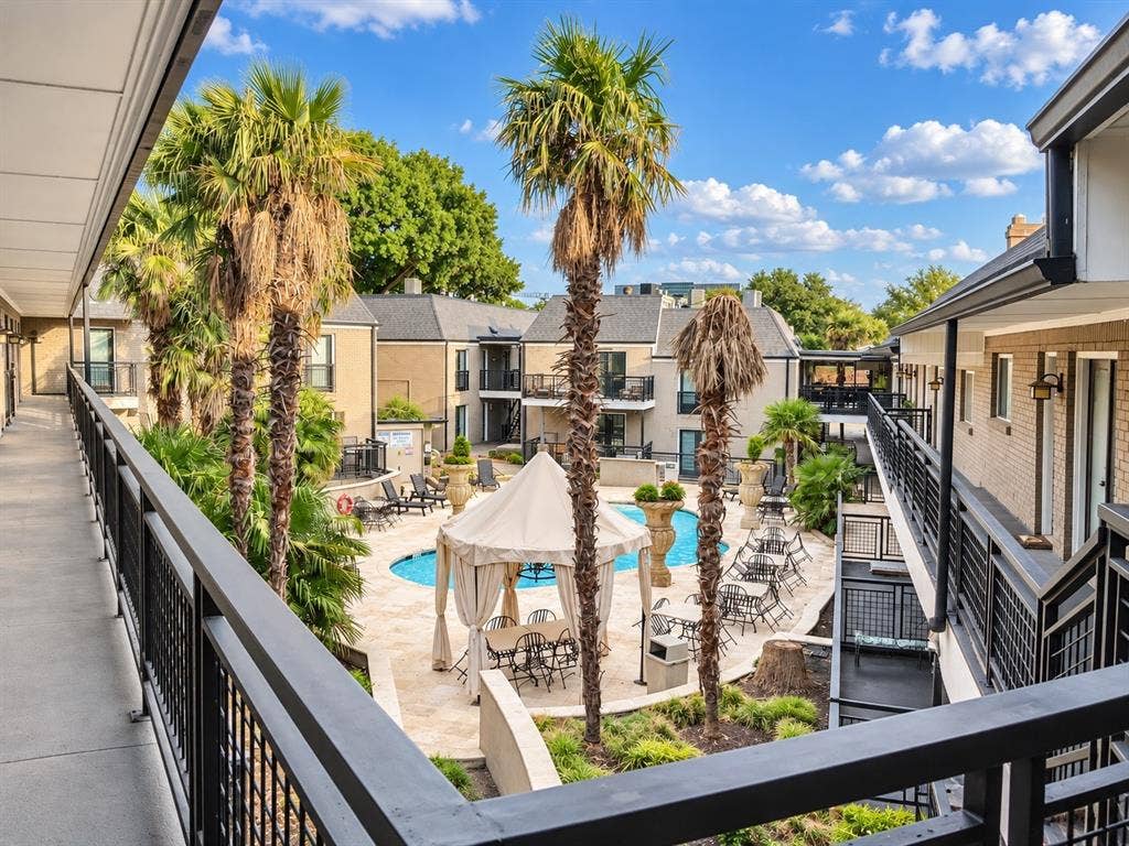 7730 Meadow Park Drive, #222, Dallas, TX 75230 Courtyard featuring a swimming pool, stone-finish decking, mature palm trees, and metal railing accents