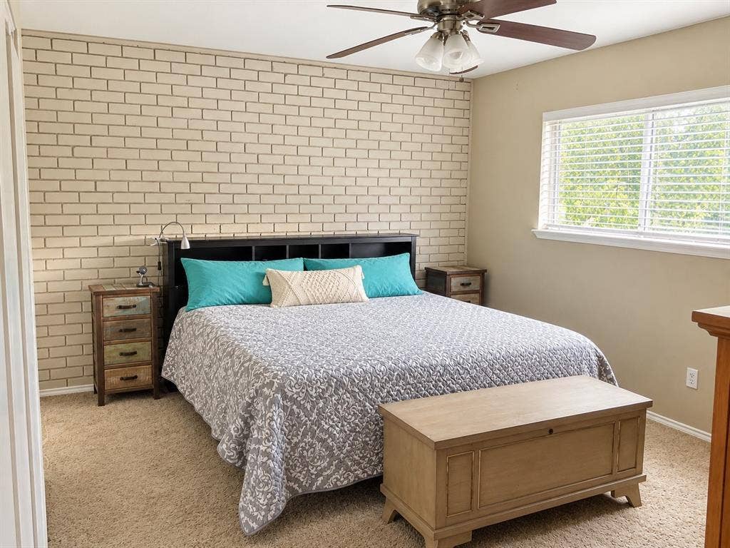 7730 Meadow Park Drive, #222, Dallas, TX 75230 Light-toned brick accent wall, neutral carpeting, and a ceiling fan with integrated lighting