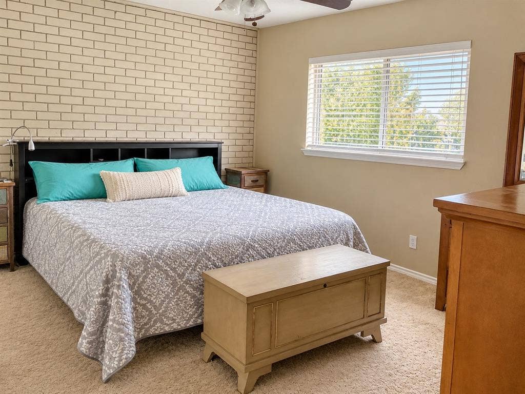 7730 Meadow Park Drive, #222, Dallas, TX 75230 Textured brick accent wall, neutral carpeting, and a double-pane window with installed blinds