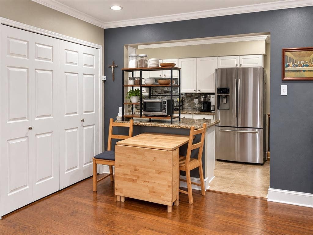 7730 Meadow Park Drive, #222, Dallas, TX 75230 Kitchen featuring white shaker-style cabinetry, stone-finish countertops, stainless steel refrigerator, neutral tile flooring, and wood-finish flooring