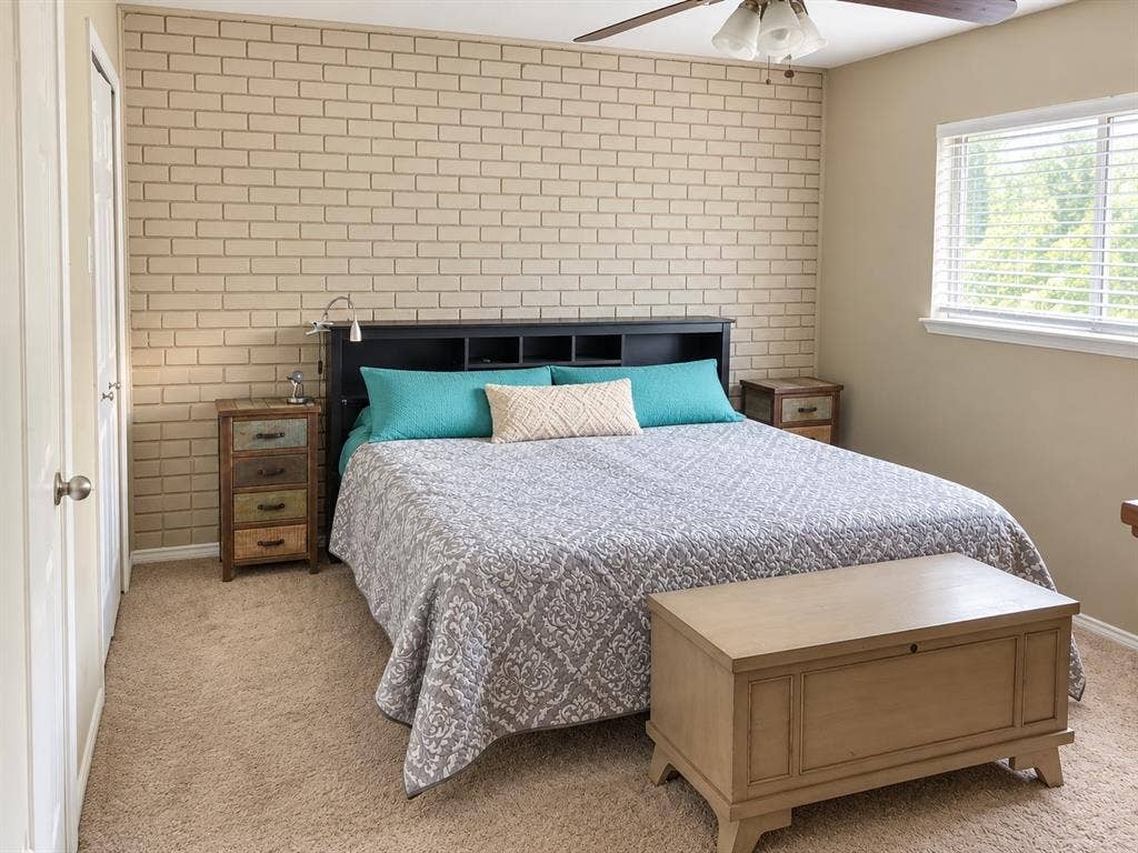 7730 Meadow Park Drive, #222, Dallas, TX 75230 Neutral-toned brick accent wall, carpeted flooring, window with horizontal blinds, and ceiling fan with integrated lighting