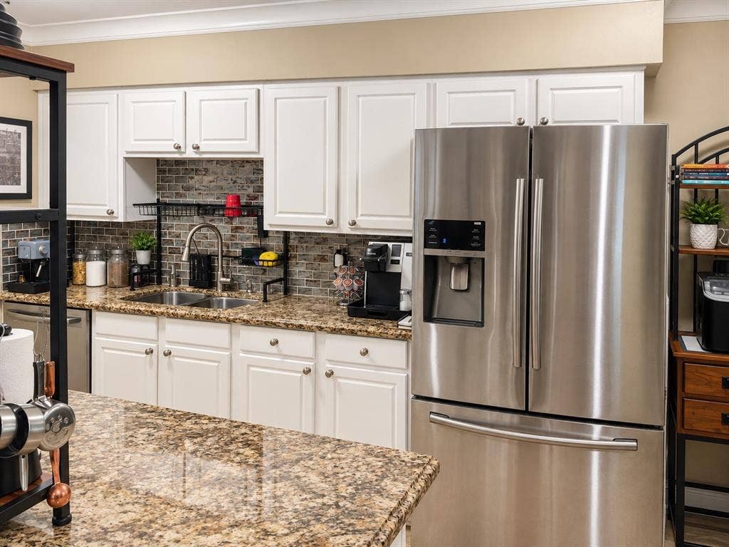 7730 Meadow Park Drive, #222, Dallas, TX 75230 Kitchen featuring white cabinetry, stone-surface countertops, a stainless steel refrigerator, and a brick-finish backsplash
