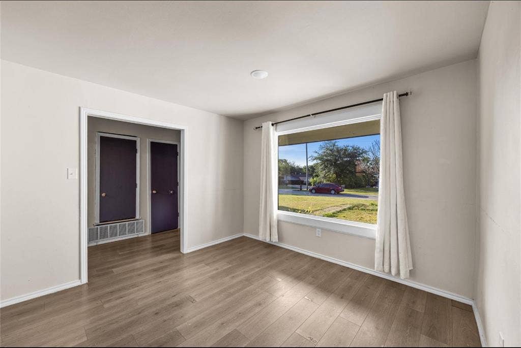 Room featuring wood-finish flooring, a large picture window, and neutral wall paint
