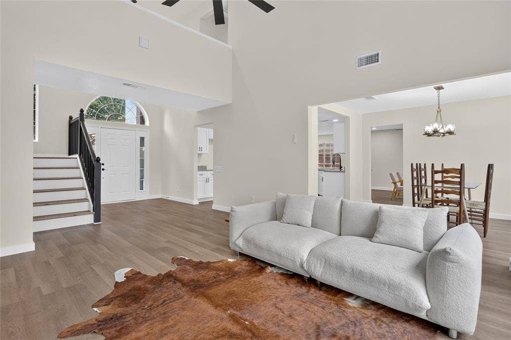 Vaulted ceilings, wood-finish flooring, staircase with a black handrail, arched transom window, and multi-light hanging chandelier