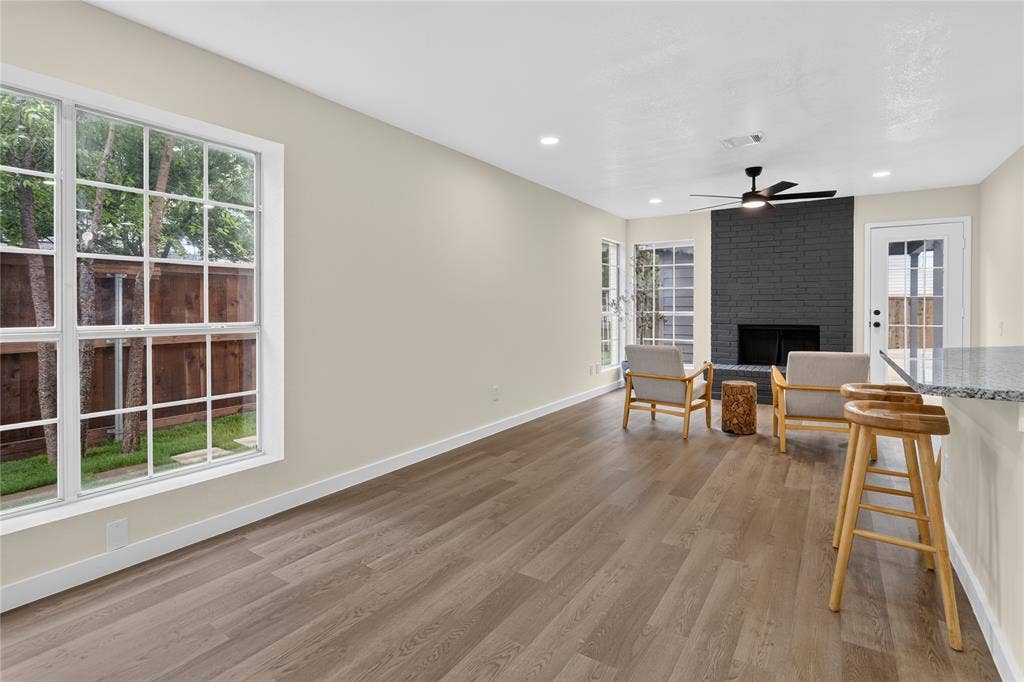 Wood-finish flooring, recessed lighting, ceiling fan, painted brick fireplace, and grid-pattern windows