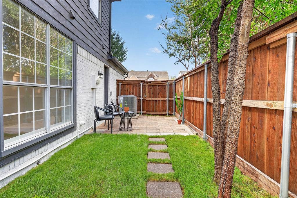 Side yard featuring a paver patio, grass lawn, stone stepping stones, and wood privacy fencing