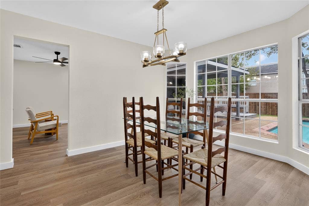 Dining area featuring wood-finish flooring, a multi-light metal chandelier, and large windows with exterior views