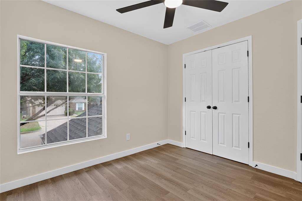 Interior space featuring wood-finish flooring, a multi-pane grid window, double doors with matte black hardware, and a ceiling fan with integrated lighting