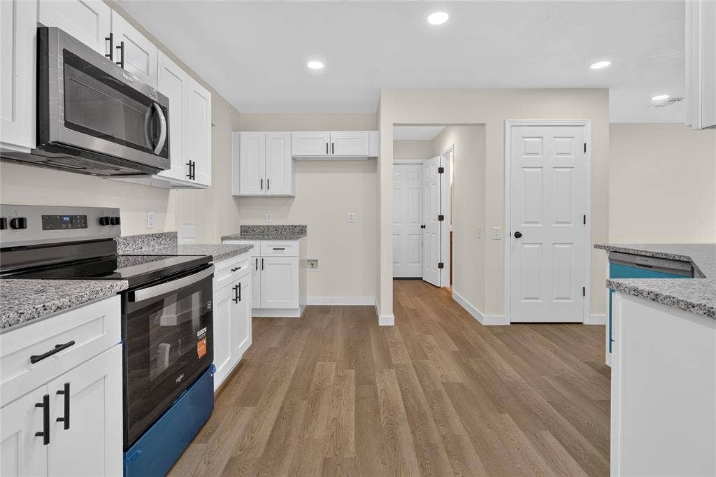 Kitchen featuring white cabinetry, stone-finish countertops, stainless steel appliances, recessed lighting, and wood-finish flooring