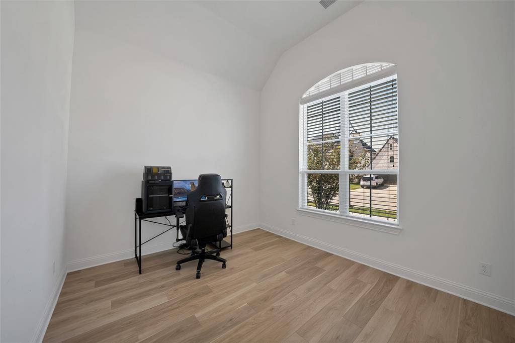 Room featuring wood-finish flooring, vaulted ceilings, and a tall window with an arched transom