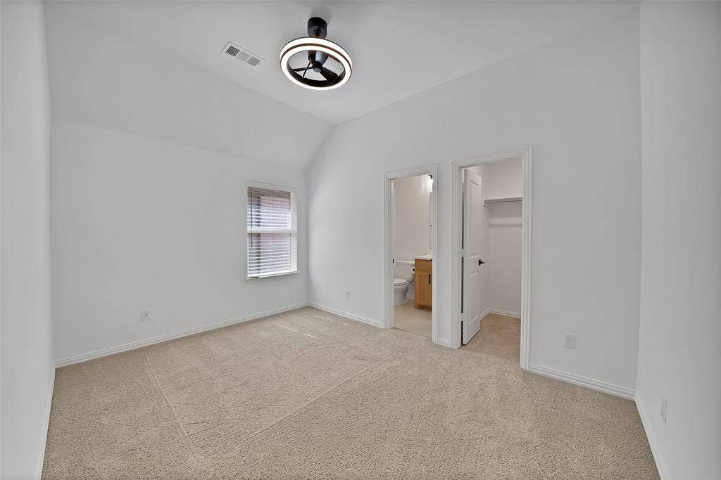 Vaulted ceiling room featuring neutral carpeting, a modern circular LED light fixture, and an integrated closet