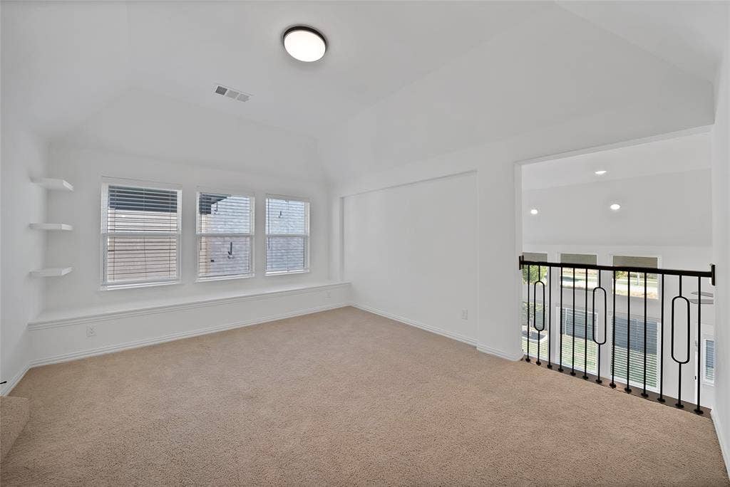 Vaulted ceiling, built-in wall shelving, integrated window bench seating, and decorative black metal railing