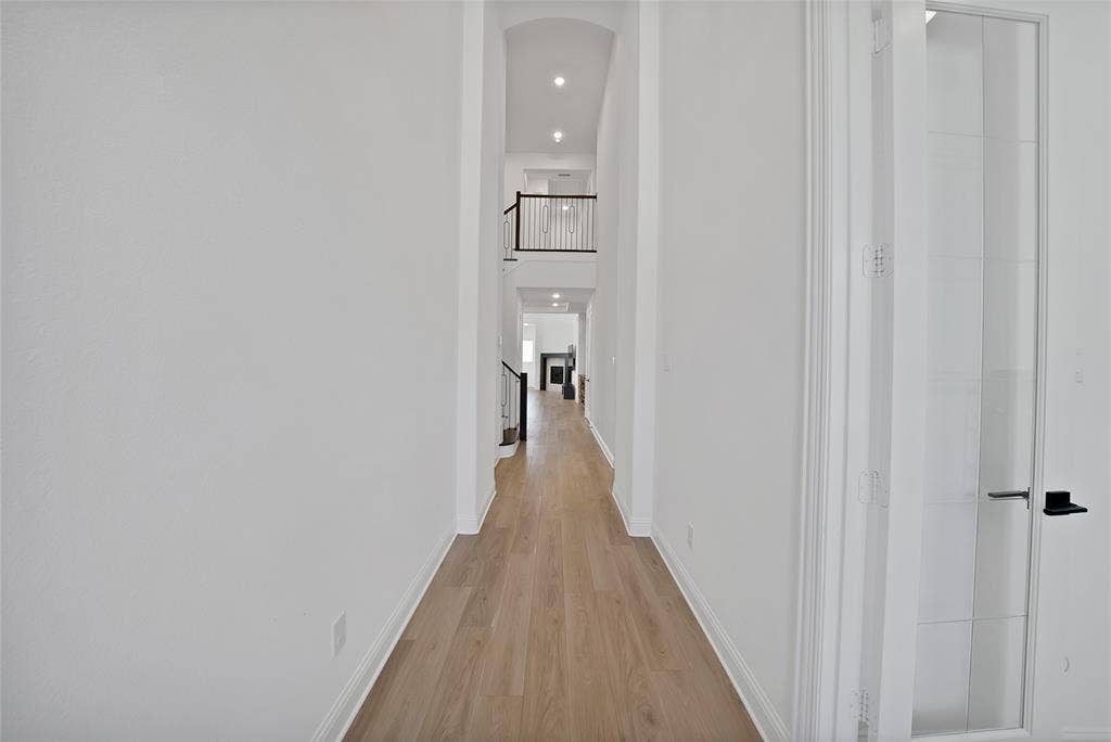 Vaulted ceilings, wood-finish flooring, recessed lighting, and a staircase featuring metal balusters