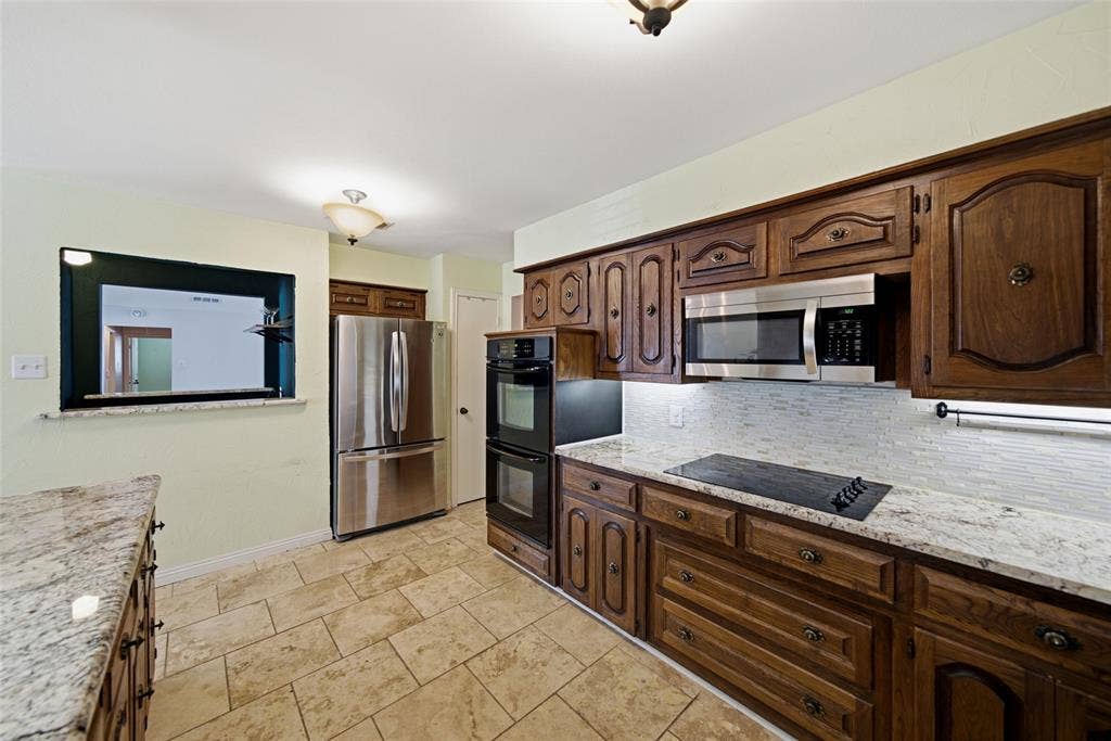 467 Harvest Glen Drive, Richardson, TX 75081 Kitchen featuring stone-surface countertops, stone-finish tile flooring, wood cabinetry, built-in double wall ovens, and stainless steel refrigerator