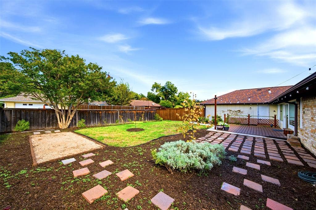 467 Harvest Glen Drive, Richardson, TX 75081 Private backyard featuring a paved stone patio, elevated wood-finish deck, sand-filled recreation area, and wood privacy fencing