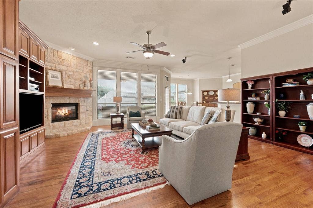 Living area featuring wood-finish flooring and a stone-clad fireplace with a wood mantle