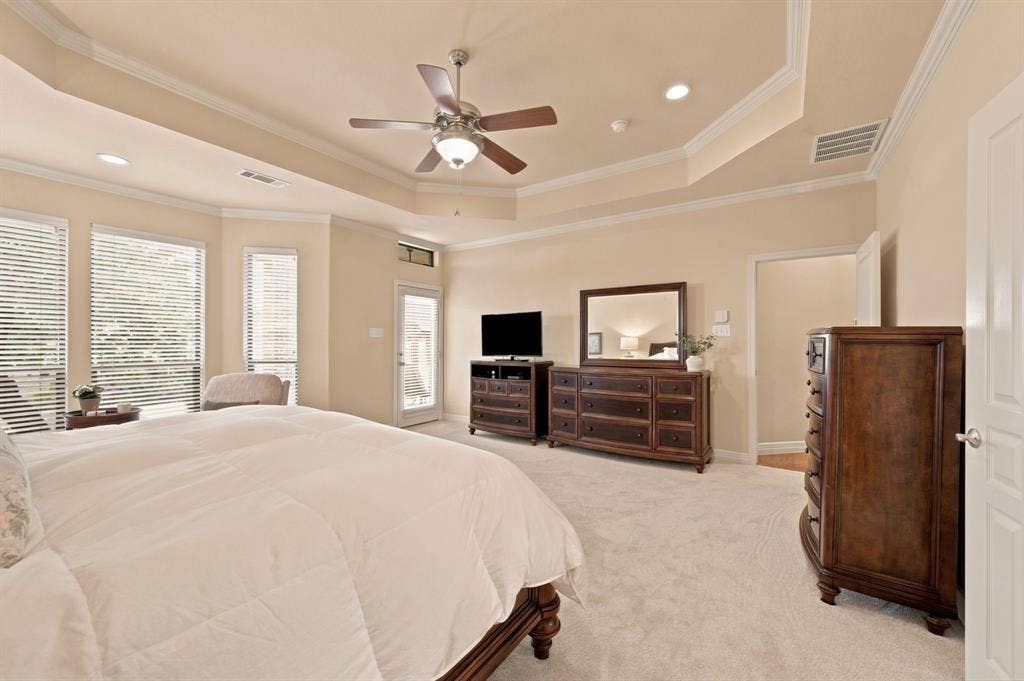 Expansive room featuring a tray ceiling with crown molding, ceiling fan, and recessed lighting