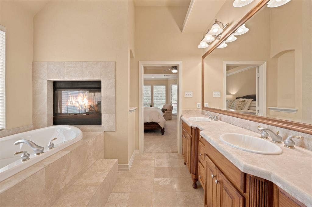 Bathroom featuring a built-in fireplace, a white soaking tub, and tile surround
