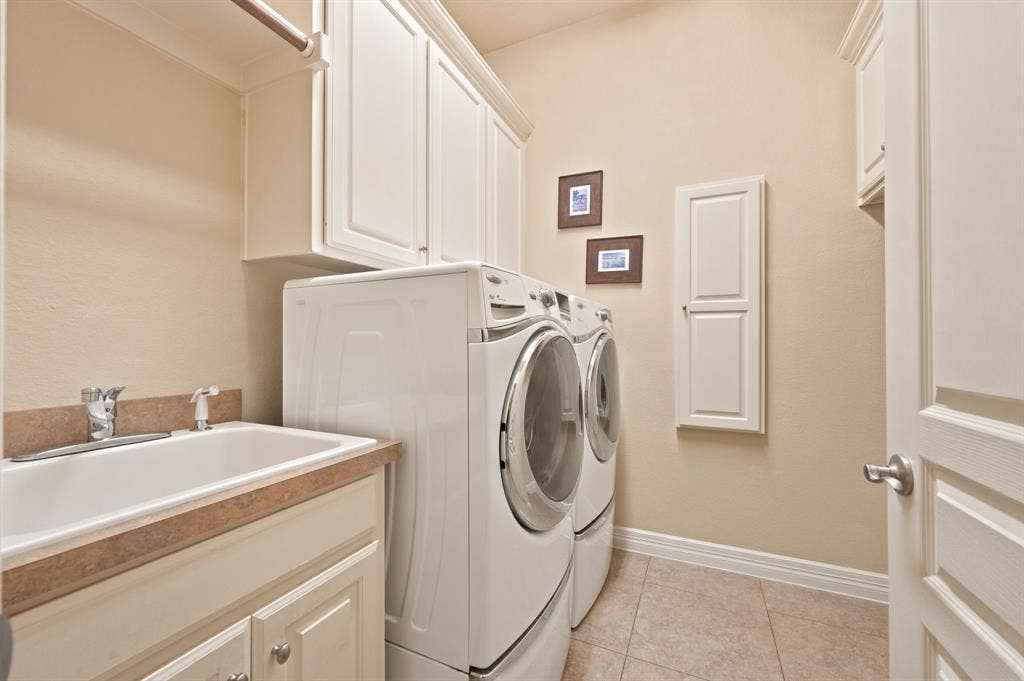Utility room featuring a utility sink, light-toned countertop, and extensive upper and lower cabinetry