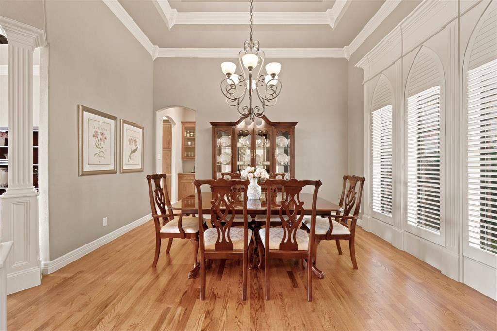 Formal dining area featuring wood-finish flooring, a tray ceiling with crown molding, and an ornate chandelier