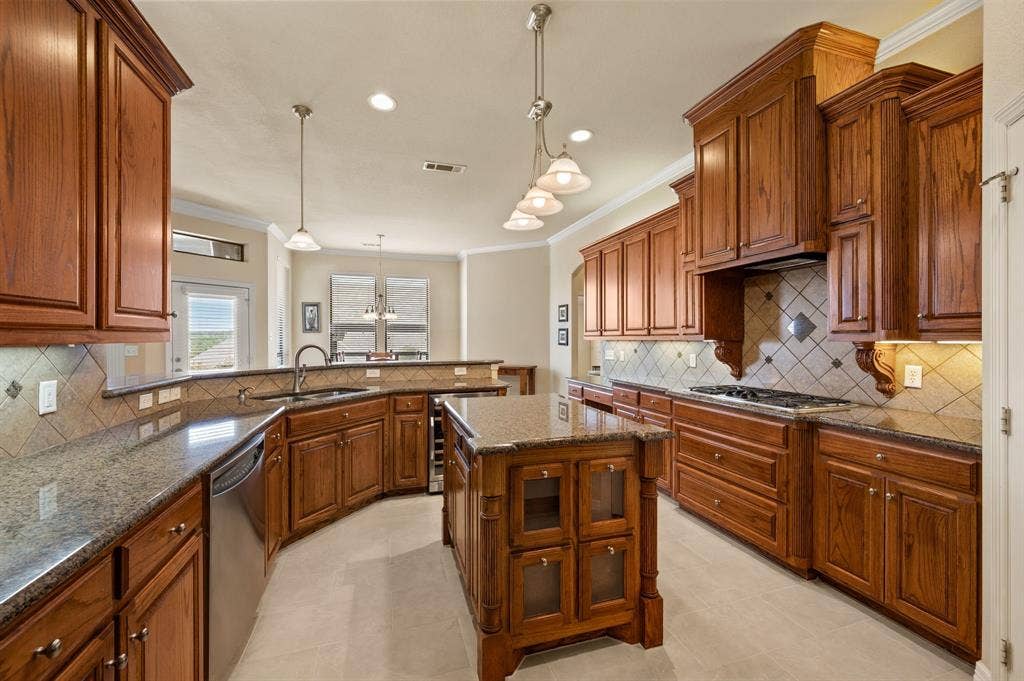 Kitchen featuring natural wood cabinetry, central island, stone-finish countertops, tile backsplash, and stainless steel appliances