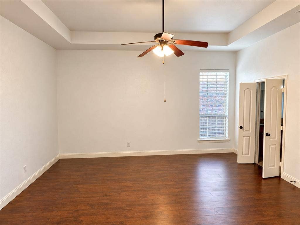 1731 Teakwood Drive, Wylie, TX 75098 Tray ceiling, wood-finish flooring, ceiling fan with integrated lighting, and dual-panel interior doors