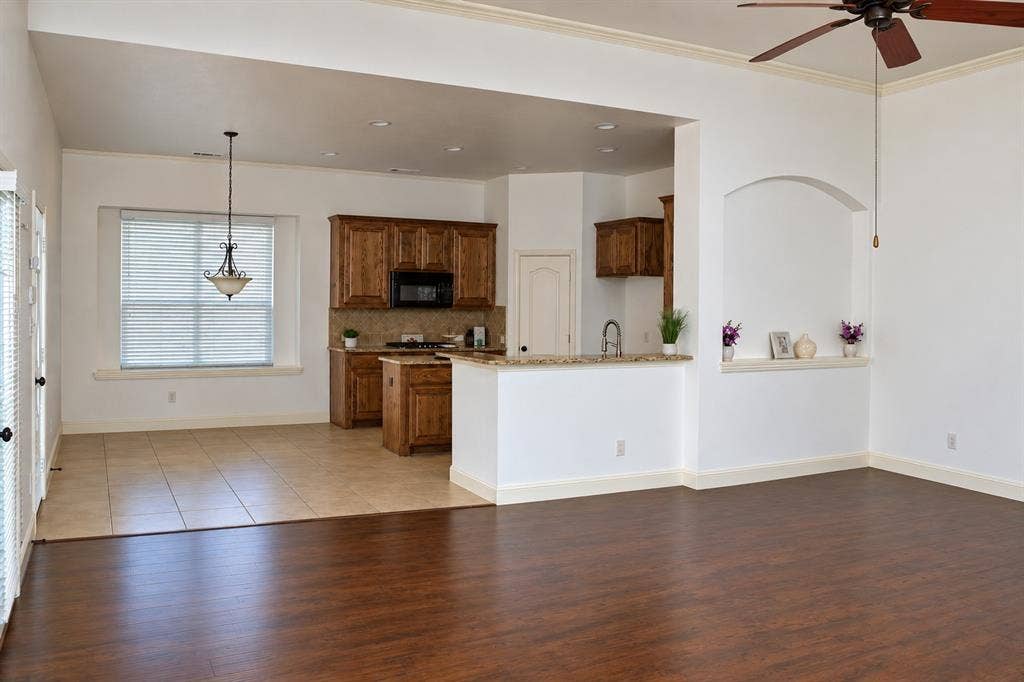 1731 Teakwood Drive, Wylie, TX 75098 Open-concept interior featuring wood-finish flooring, tile kitchen flooring, ceiling-mounted paddle fan, recessed lighting, and a built-in arched alcove