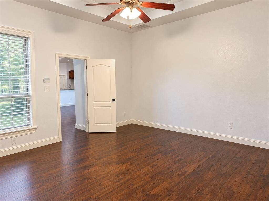 1731 Teakwood Drive, Wylie, TX 75098 Room featuring wood-finish flooring, tray ceiling, ceiling fan with integrated lighting, and multi-pane window with blinds