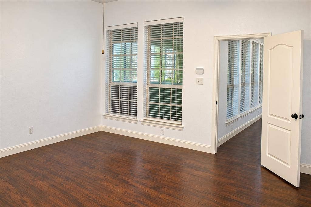 1731 Teakwood Drive, Wylie, TX 75098 Wood-finish flooring, dual windows with horizontal blinds, and a solid-core interior door with matte black hardware