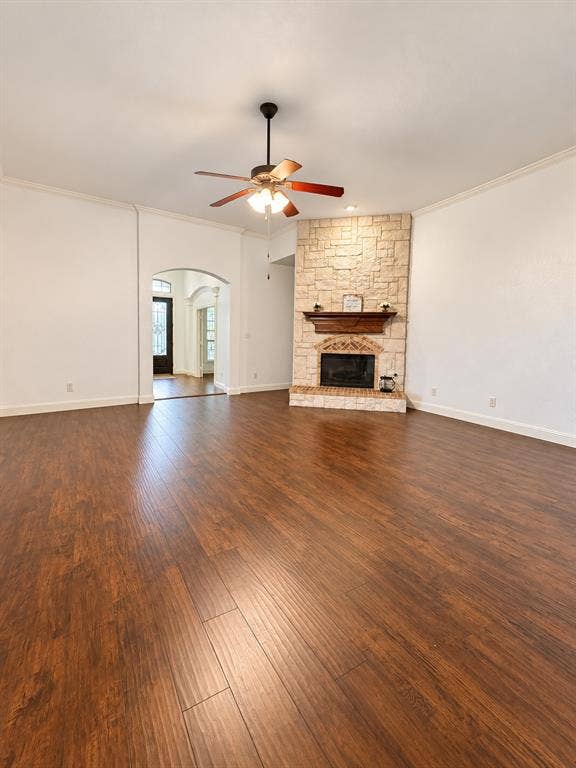 1731 Teakwood Drive, Wylie, TX 75098 Living area featuring wood-finish flooring, a floor-to-ceiling masonry fireplace with a wooden mantel, crown molding, a ceiling fan with integrated lighting, and an arched entryway