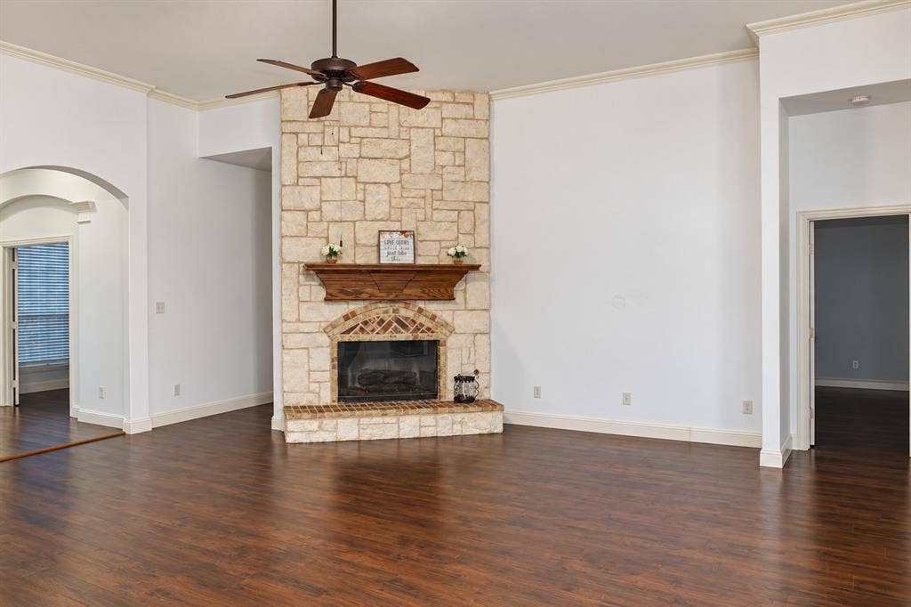 1731 Teakwood Drive, Wylie, TX 75098 Living area featuring wood-finish flooring, a floor-to-ceiling masonry fireplace with a wood mantel, a ceiling fan, and arched architectural detailing