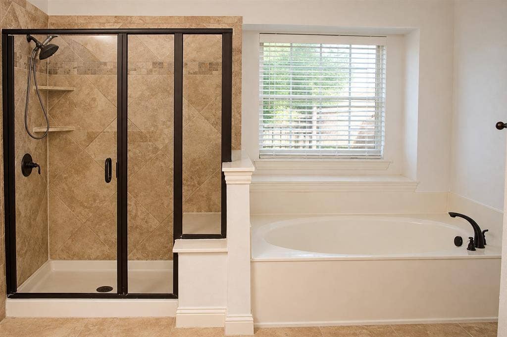 1731 Teakwood Drive, Wylie, TX 75098 Walk-in shower with diamond-pattern tile surrounds, oil-rubbed bronze fixtures, built-in shelving, glass enclosure, and a separate soaking tub