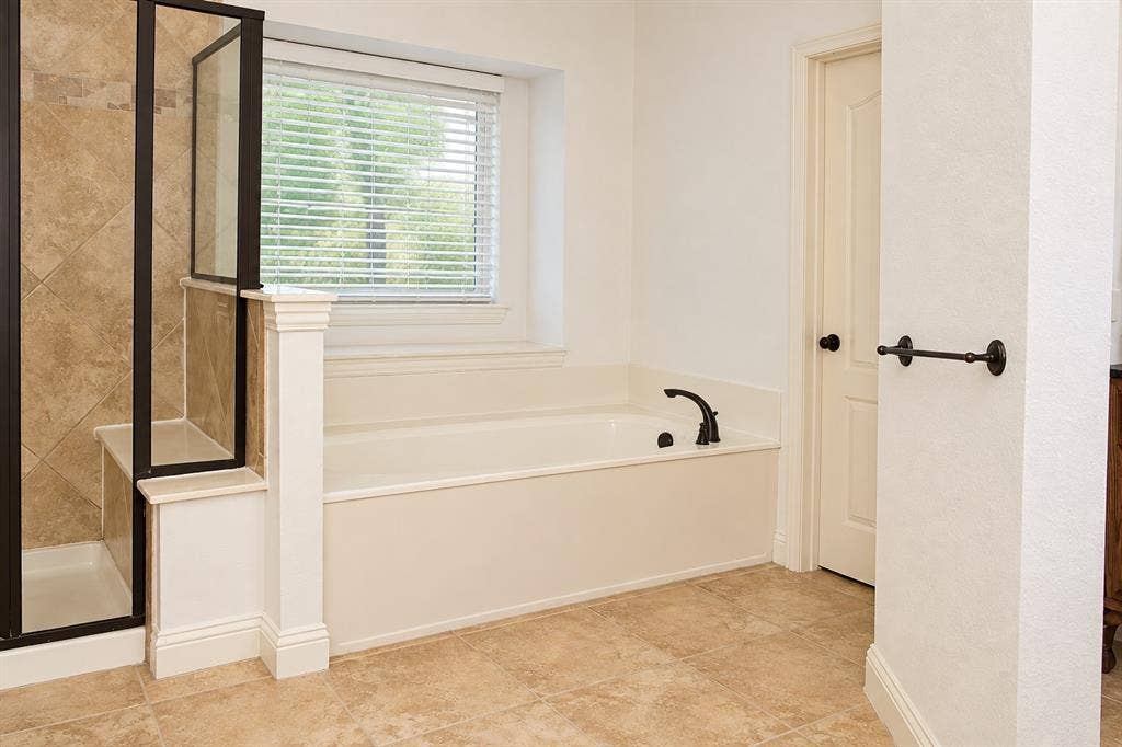 1731 Teakwood Drive, Wylie, TX 75098 Soaking tub with a deck-mounted faucet, walk-in shower with tiled surround, and large-format tile flooring