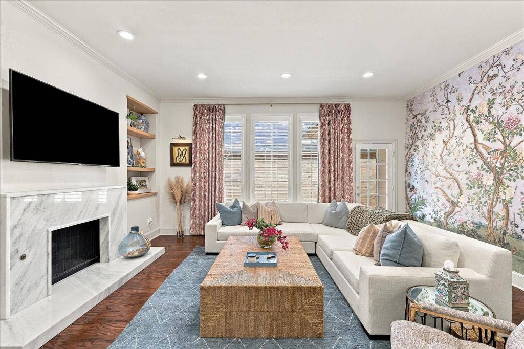 Spacious living space with marble fireplace, Shumacher wallpaper, and a wall of windows.