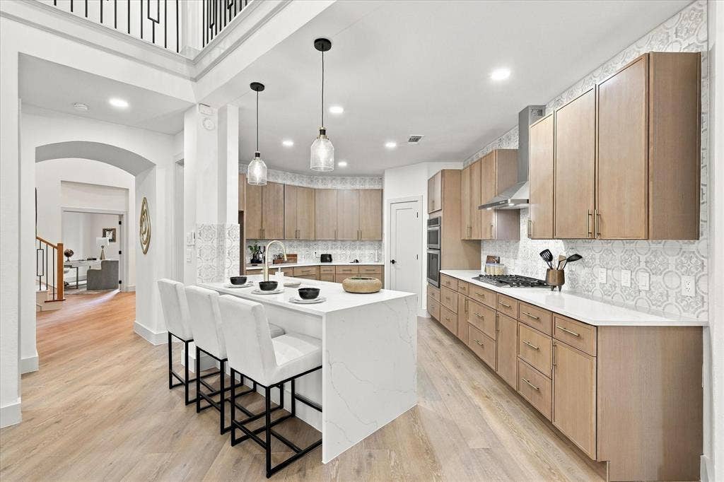 5609 Hillview Court, McKinney, TX 75072 Kitchen featuring a large central island with a stone countertop, flat-panel wood cabinetry, patterned tile backsplash, stainless steel gas cooktop with range hood, and wood-finish flooring