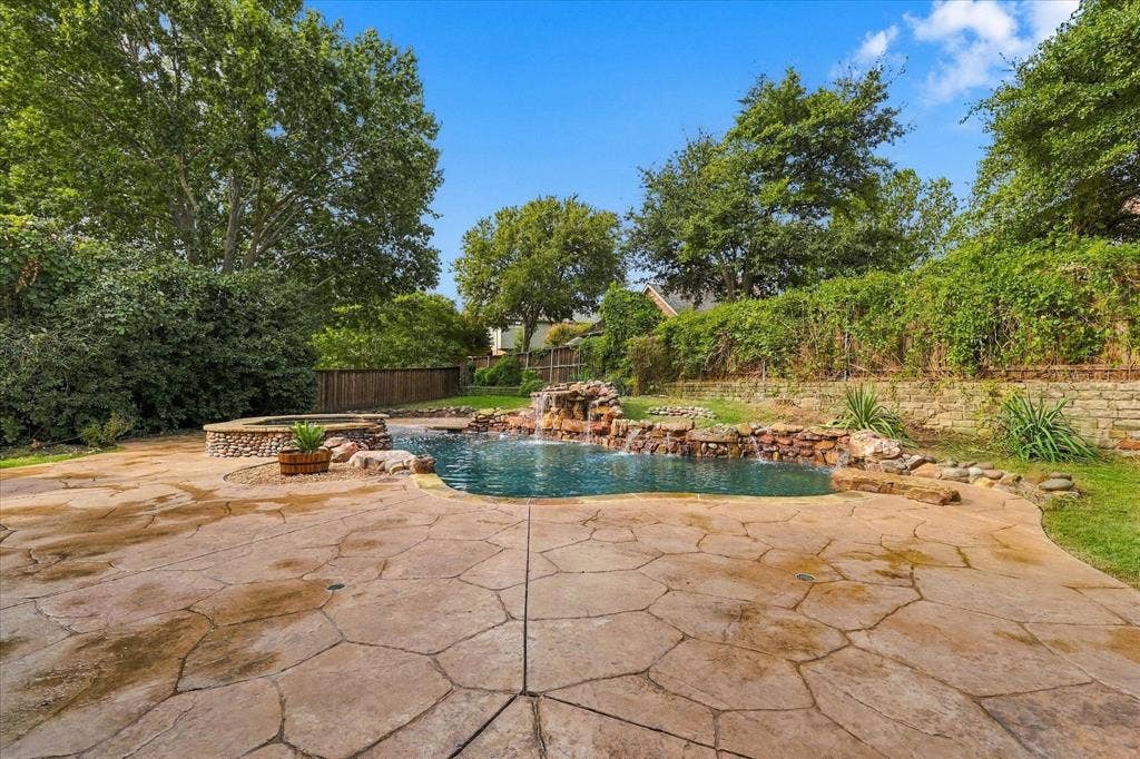 5609 Hillview Court, McKinney, TX 75072 Outdoor oasis featuring a flagstone patio, natural rock-accented pool, integrated stone waterfall, raised spa, and stone retaining wall