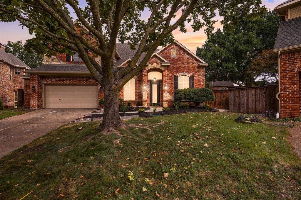 5609 Hillview Court, McKinney, TX 75072 Traditional brick exterior featuring an arched entryway, gabled rooflines, attached two-car garage, and mature tree landscaping