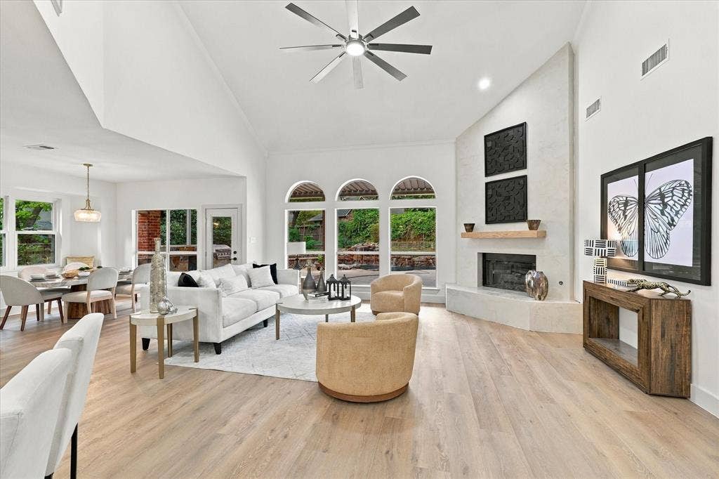 5609 Hillview Court, McKinney, TX 75072 Vaulted ceilings with a multi-blade ceiling fan, expansive wood-finish flooring, floor-to-ceiling stone-faced fireplace with a natural wood mantel, and arched windows