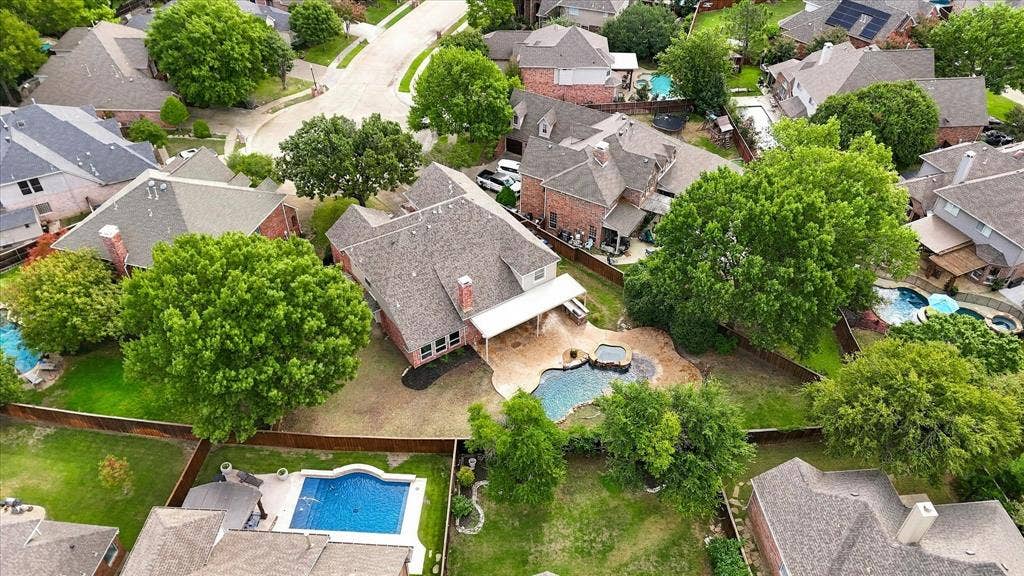5609 Hillview Court, McKinney, TX 75072 Aerial view of a residential property featuring a brick exterior, a covered patio, an in-ground swimming pool, a separate spa, and mature trees