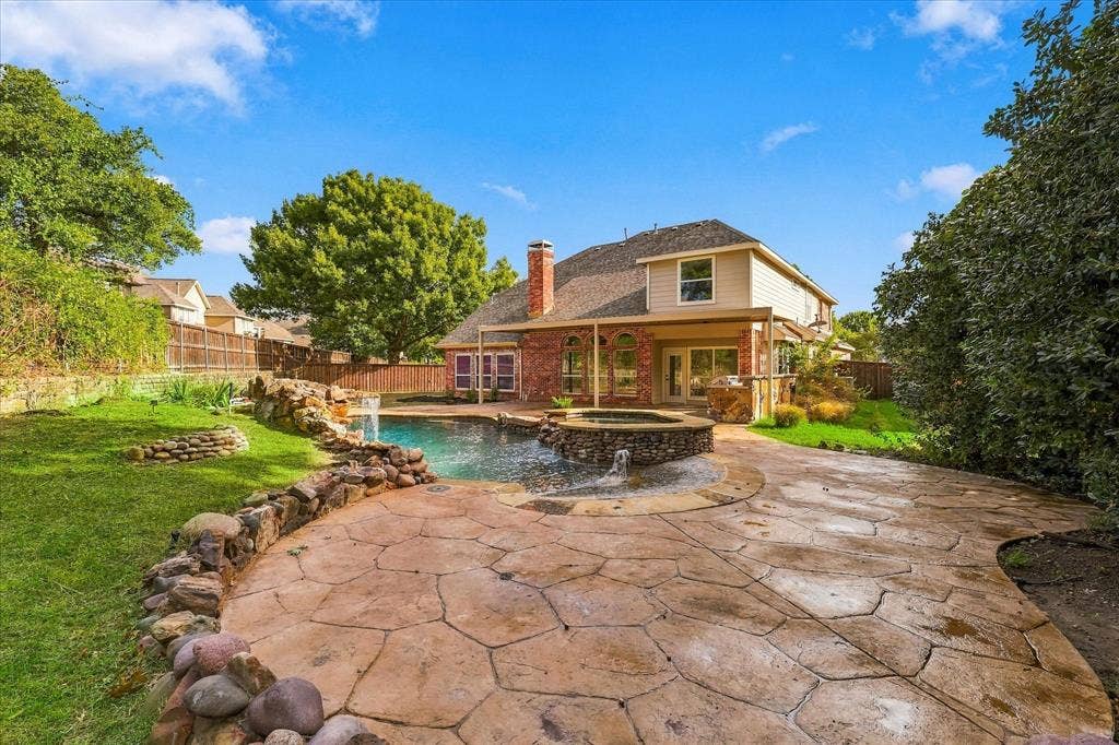 5609 Hillview Court, McKinney, TX 75072 Backyard featuring an in-ground swimming pool with an integrated stone spa, stone water feature, decorative stamped concrete patio, and a covered rear porch