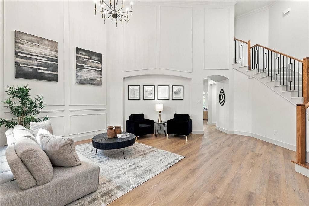 5609 Hillview Court, McKinney, TX 75072 Two-story foyer featuring paneled walls, wood-finish flooring, a tiered chandelier, and a staircase with metal balusters and wood handrails