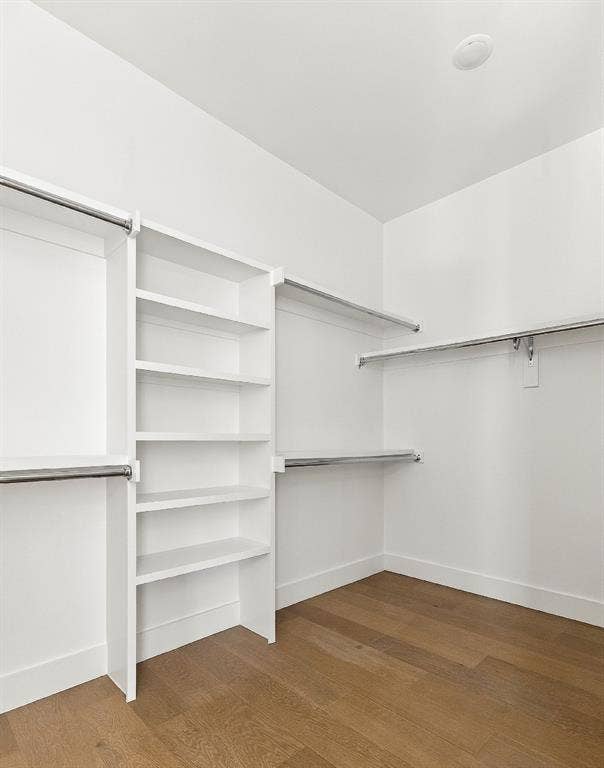 4953 Forest Bend Road, Dallas, TX 75244 Walk-in closet featuring white built-in shelving, multi-level metal garment rods, and wood-finish flooring