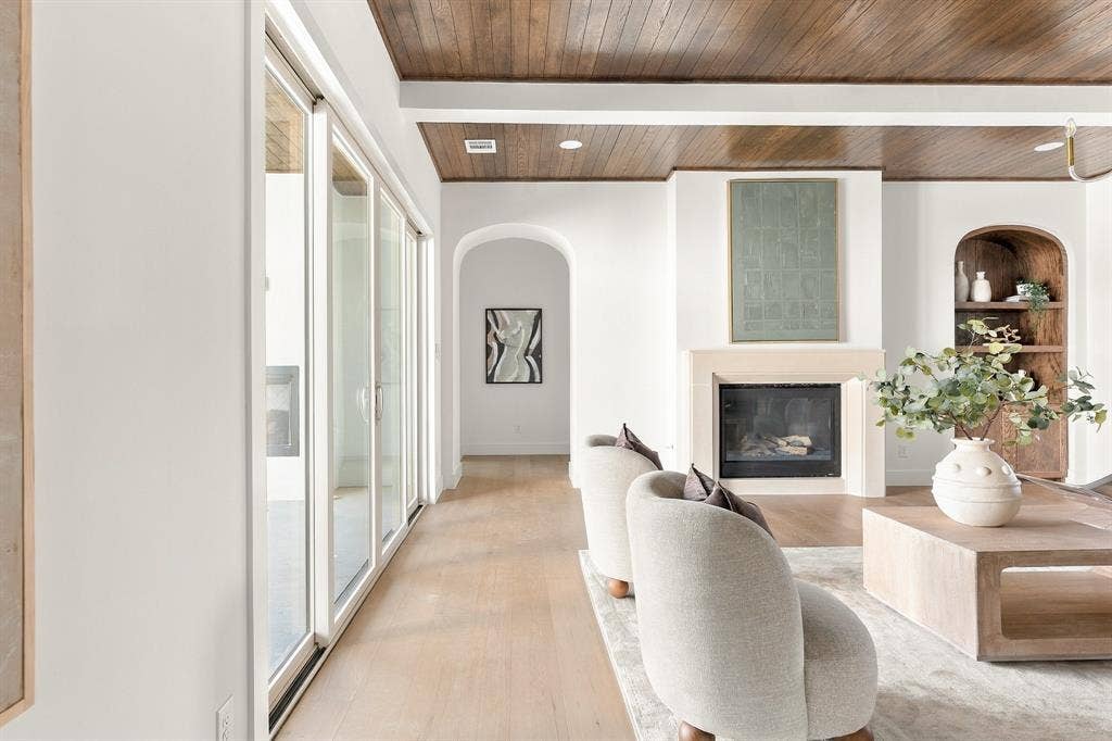 4953 Forest Bend Road, Dallas, TX 75244 Living space featuring a wood-plank ceiling, floor-to-ceiling glass sliding doors, a fireplace with a neutral surround, an arched built-in display niche, and light-toned wood-finish flooring