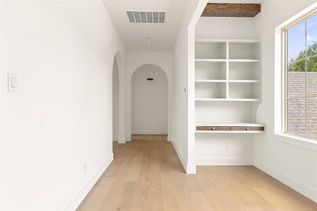 4953 Forest Bend Road, Dallas, TX 75244 Built-in shelving, integrated desk, wood-finish flooring, architectural archways, and exposed wood ceiling beam