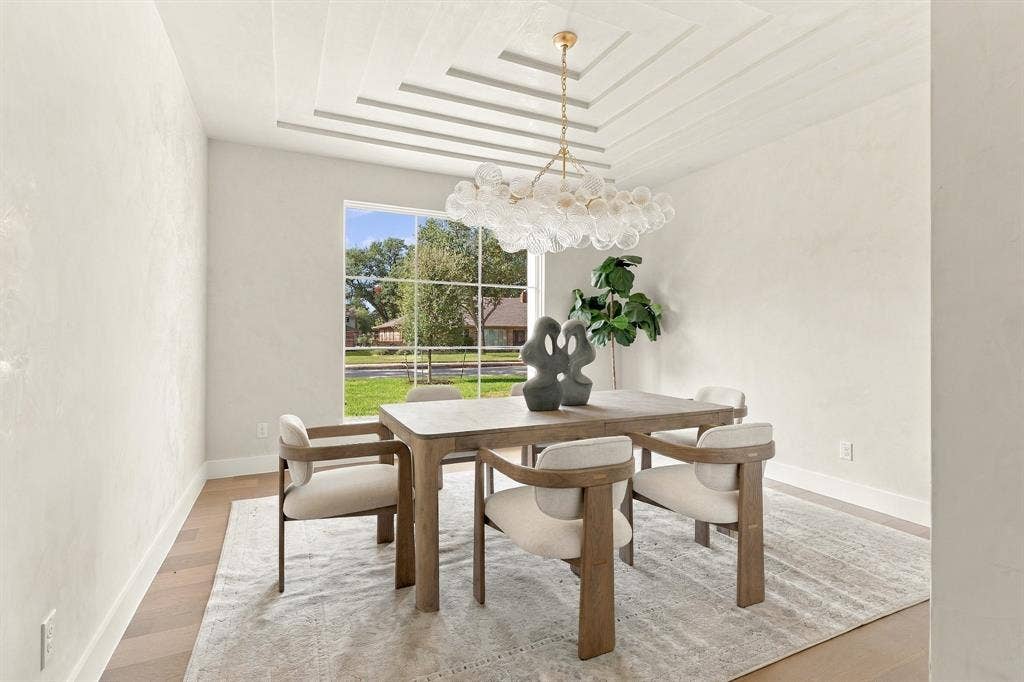 4953 Forest Bend Road, Dallas, TX 75244 Tray ceiling with recessed linear detailing, large multi-pane window, and decorative multi-globe chandelier with a metallic finish