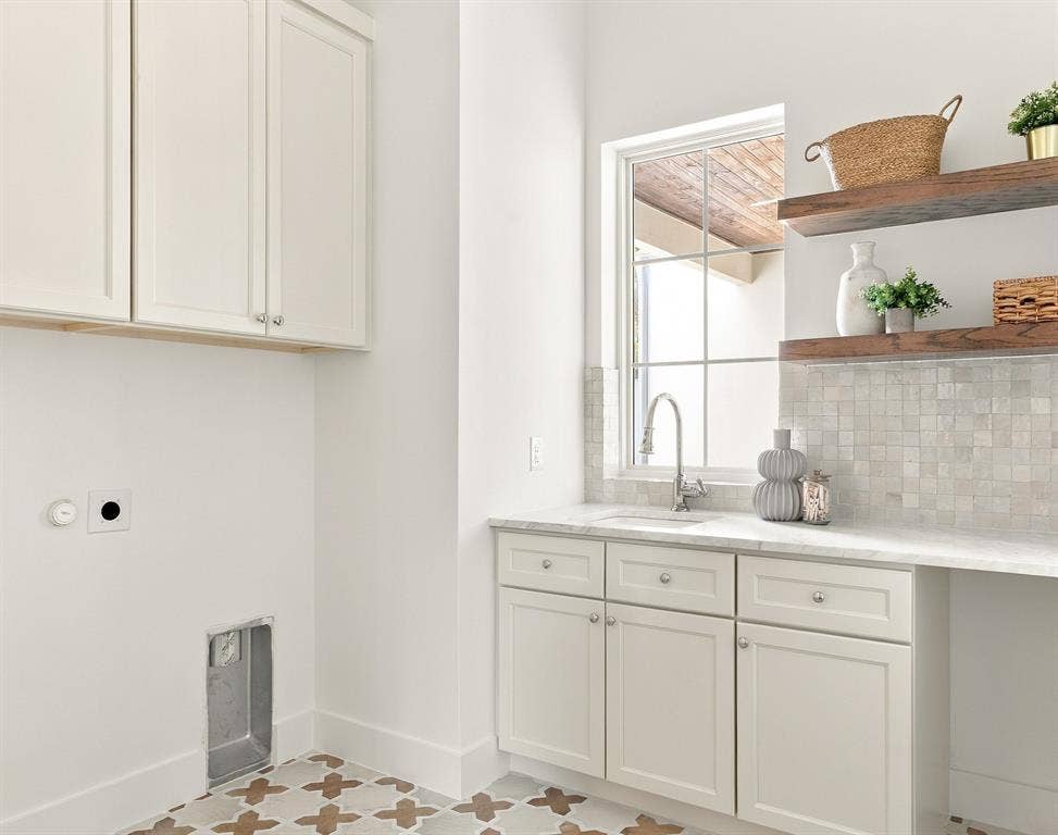 4953 Forest Bend Road, Dallas, TX 75244 Laundry area featuring shaker-style cabinetry, stone-surface countertop, tiled backsplash, wall-mounted floating wood shelves, and patterned floor tile