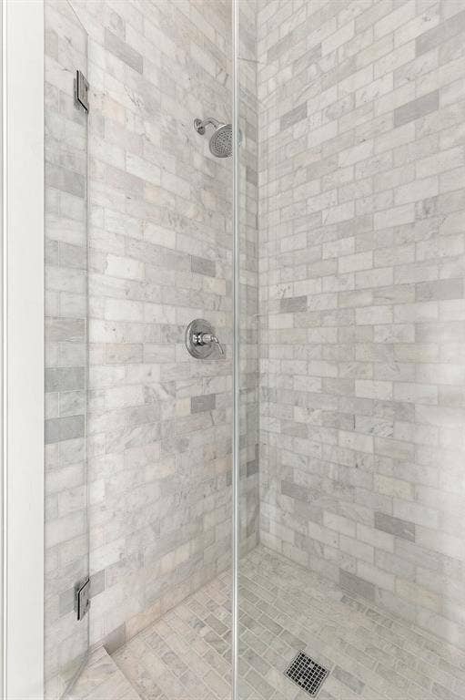 4953 Forest Bend Road, Dallas, TX 75244 Walk-in shower featuring floor-to-ceiling subway-style stone tile, a frameless glass door, and a wall-mounted shower head with integrated temperature control