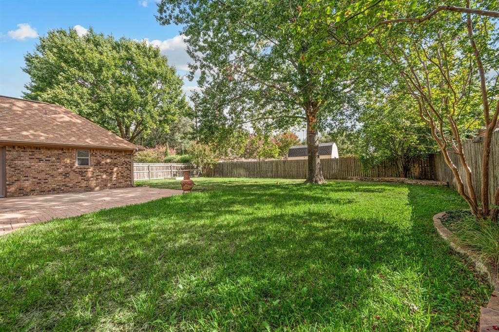 339 Park North Lane, Keller, TX 76248 Expansive backyard featuring a brick-paved patio, manicured lawn, mature trees, and perimeter wood fencing
