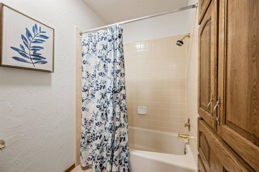 339 Park North Lane, Keller, TX 76248 Full-height built-in wood cabinetry, tub with tile surround, and brass-finish plumbing fixtures
