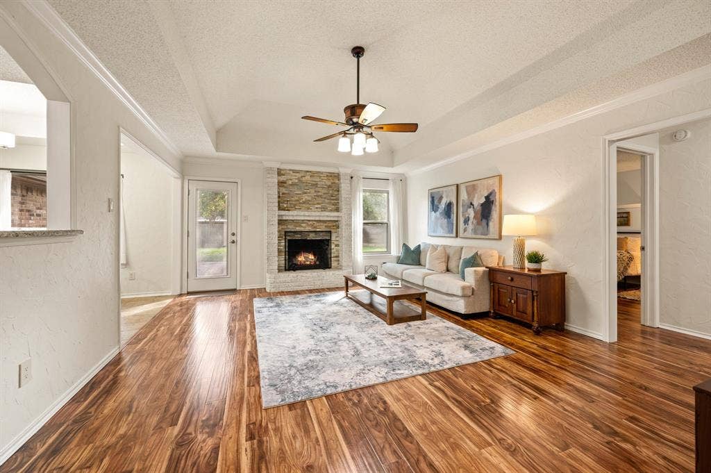 339 Park North Lane, Keller, TX 76248 Living area featuring wood-finish flooring, a vaulted ceiling with an integrated ceiling fan, and a floor-to-ceiling stone-faced fireplace with a mantel